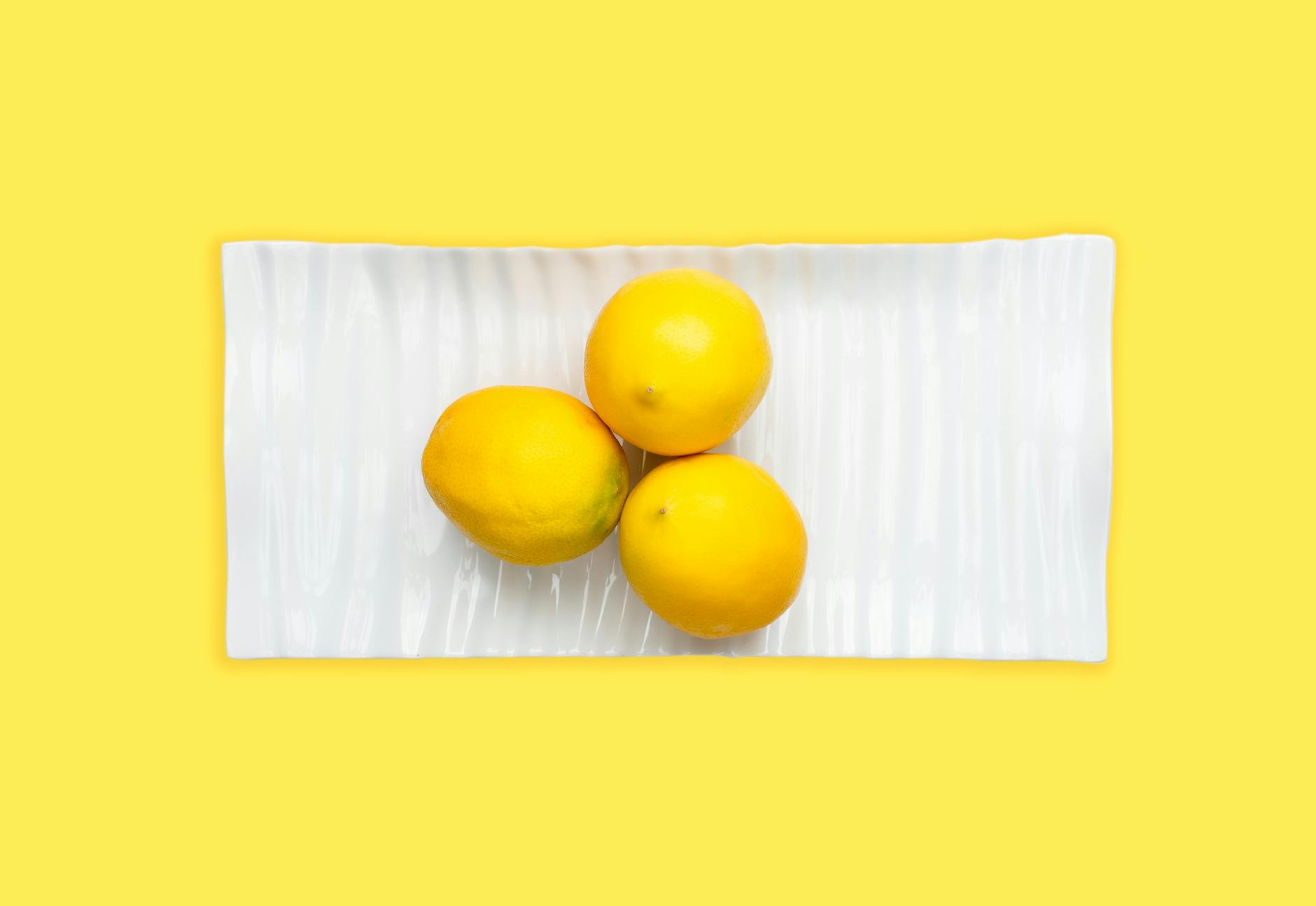 A hand holding a fresh lemon against a vivid yellow background, symbolizing renewed sensation and clarity