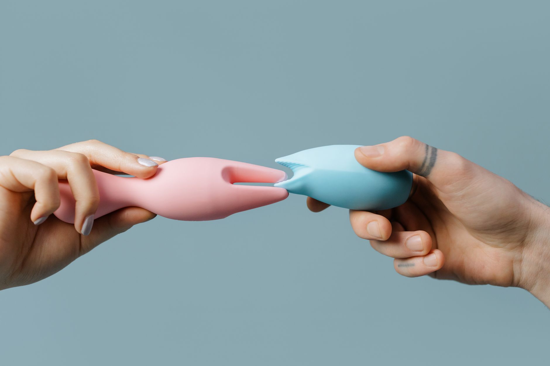 Hands holding pastel-colored silicone toys for exploration and pleasure