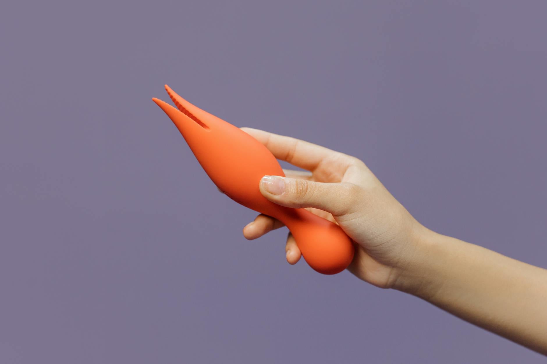 Hand holding a lemon-colored vibrator against a minimalist purple backdrop, symbolizing the restoration of sensation after stopping hormonal birth control.