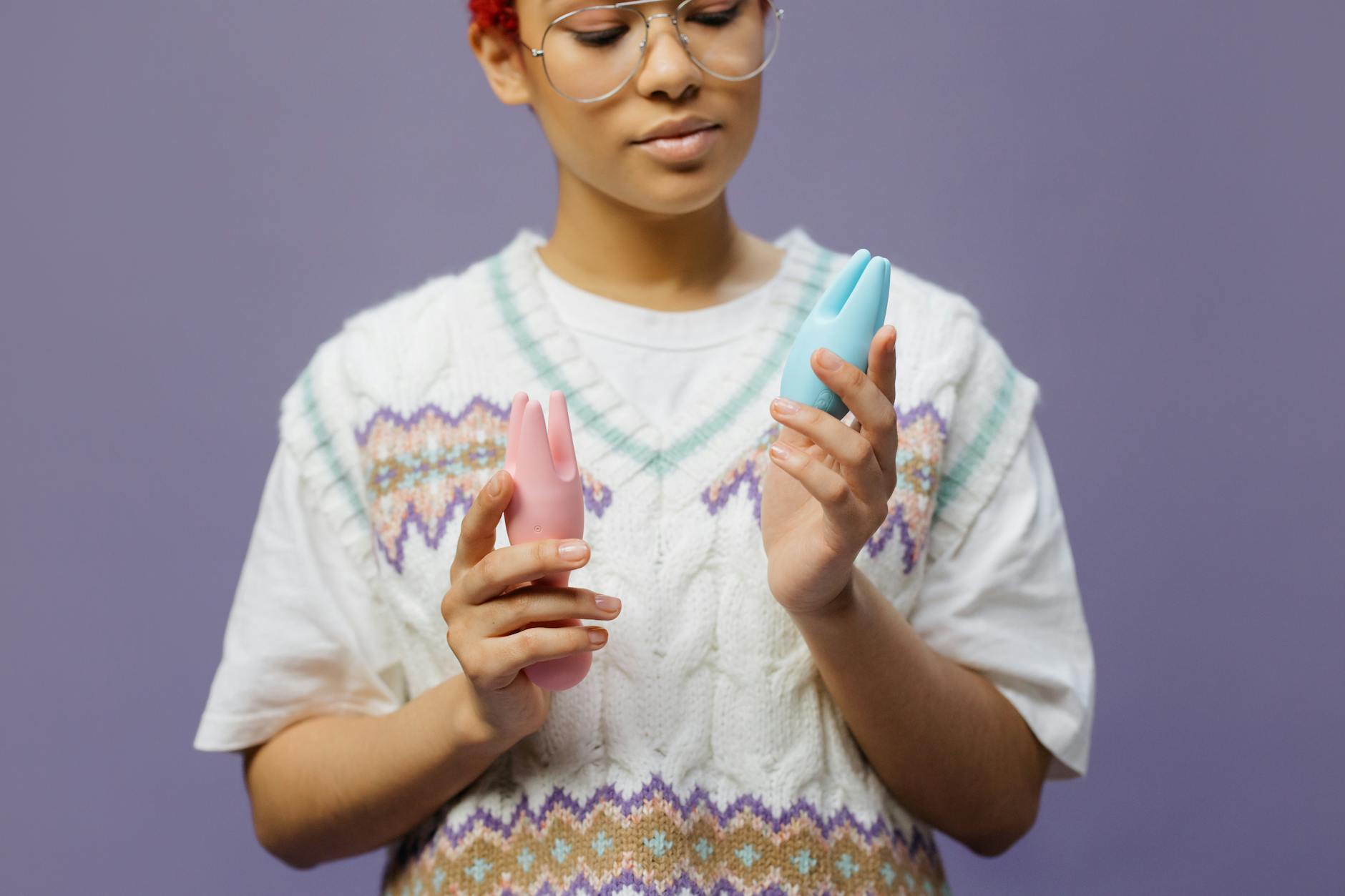 Woman holding colorful silicone vibrators in a thoughtful moment.