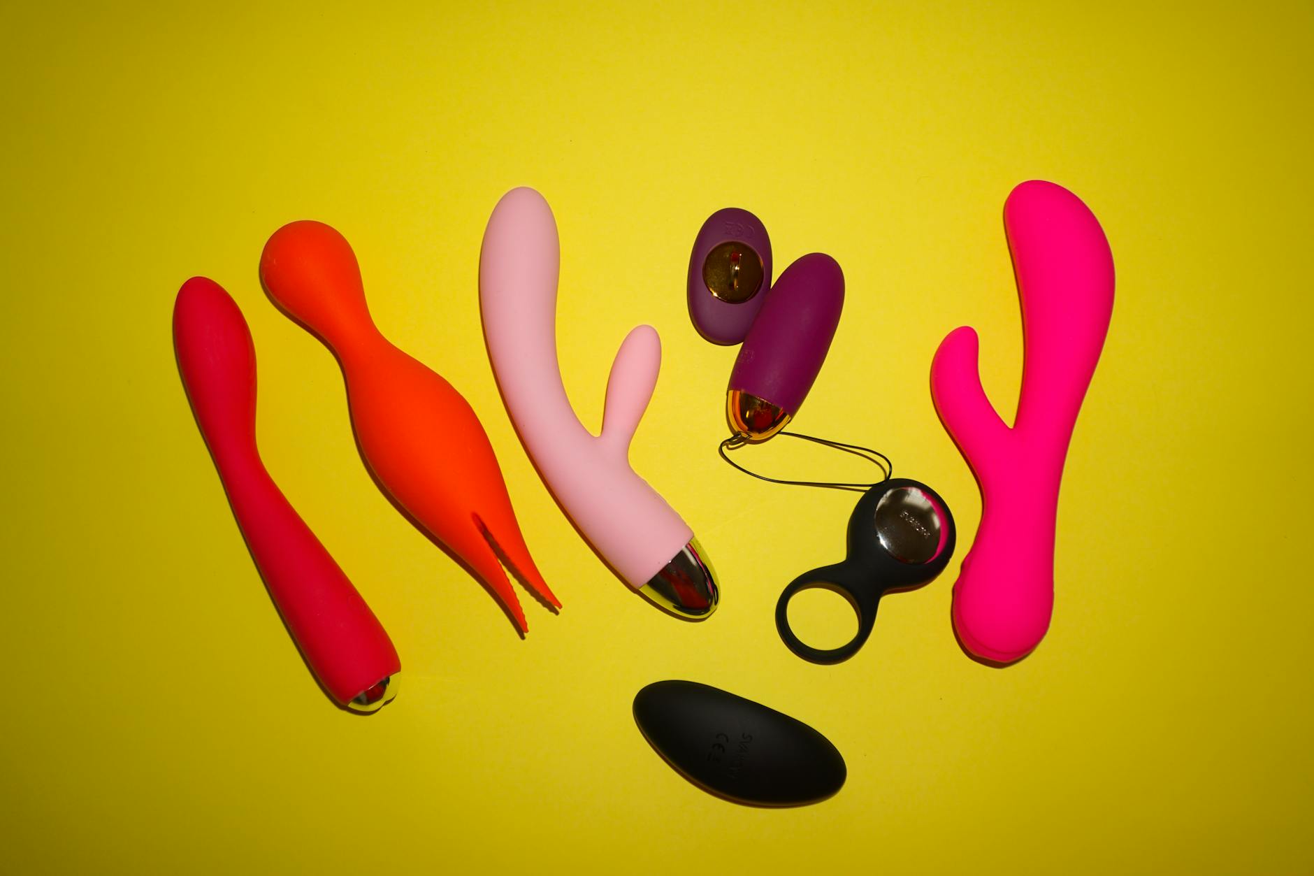 Hand holding a blue silicone vibrator against a purple background, representing personal pleasure devices and intimate self-care.